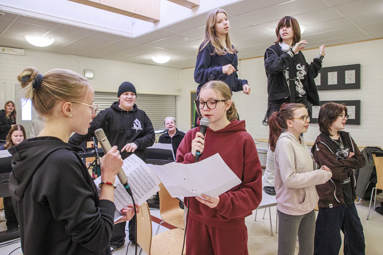 Koululaiset valitsivat itse Isoisän taskukello -musikaalin 16 kappaletta. Vas. Veera Hyöppinen, Annastiina Siltola, Lumia Lindroos, Severi Määttä, opettaja Jukka Palonen, pöydällä Anna Jantunen ja Aada Murtoniemi, edessä Helmi Sadeharju, Joanna Laakso ja Mimosa Koukkunen.