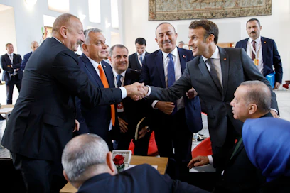 Ranskan presidentti Emmanuel Macron (oik.) kävi lokakuussa Prahassa ensimmäisen kerran kokoontuneen Euroopan poliittisen yhteisön huippukokouksessa tervehtimässä Euroopan ”pahoja poikia”. Macron kättelee Azerbaidžanin presidenttiä Ilham Aliyevia. Turkin presidentti Recep Tayyip Erdoğan (istuu oik.) ja Unkarin presidentti Viktor Orbán (toinen vas.) seuraavat.