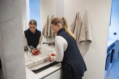 Annika Karjalainen nostaa imukupilla kylpyhuoneen lavuaarin kivitason puhdistusta varten. Lika pitää jynssätä irti parin viikon välein.