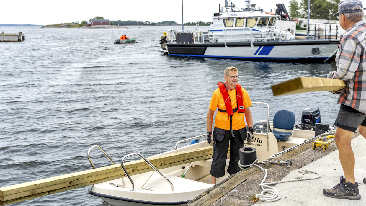 Pekka Tuomala siirtää veneeseen Haapasaaren osuuskaupan kautta tilaamaansa puutavaraa Timo Pohjolan avustuksella.