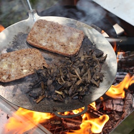 Haghus Camp Boxiin sisältyy varrellinen paistinpannu, jolla paistetaan kuvassa suppilovahveroita ja leipiä.