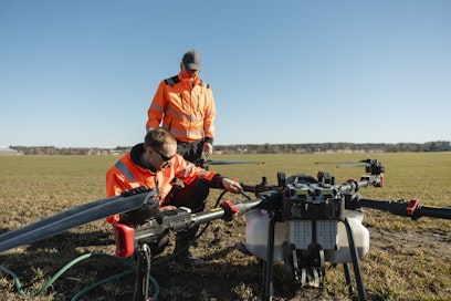 Jarmo Kattelus seuraa taustalla kun Mikko Hakojärvi valmistelee droonia lannoituslentoon. 