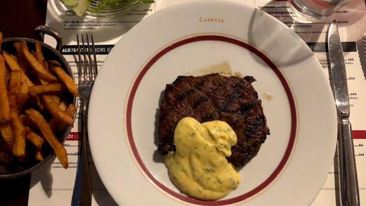 Mehevä entrecote-pihvi tarjotaan sakean kastikkeen, salaatin ja ranskanperunoiden kanssa.