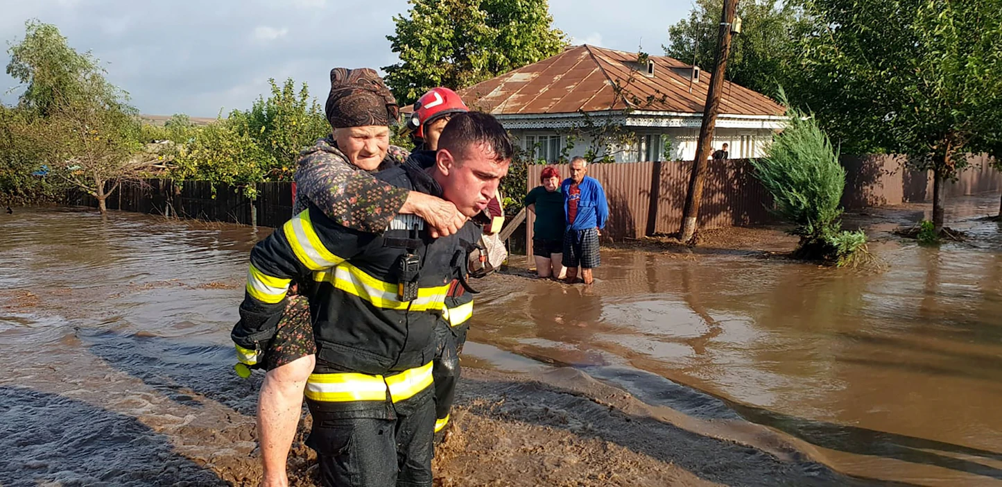 Pelastustyöntekijä kantaa iäkästä naista turvaan tulva-alueella Pecheassa Romaniassa. Handout-kuva Romanian pelastusviranomaisilta. LEHTIKUVA / AFP .