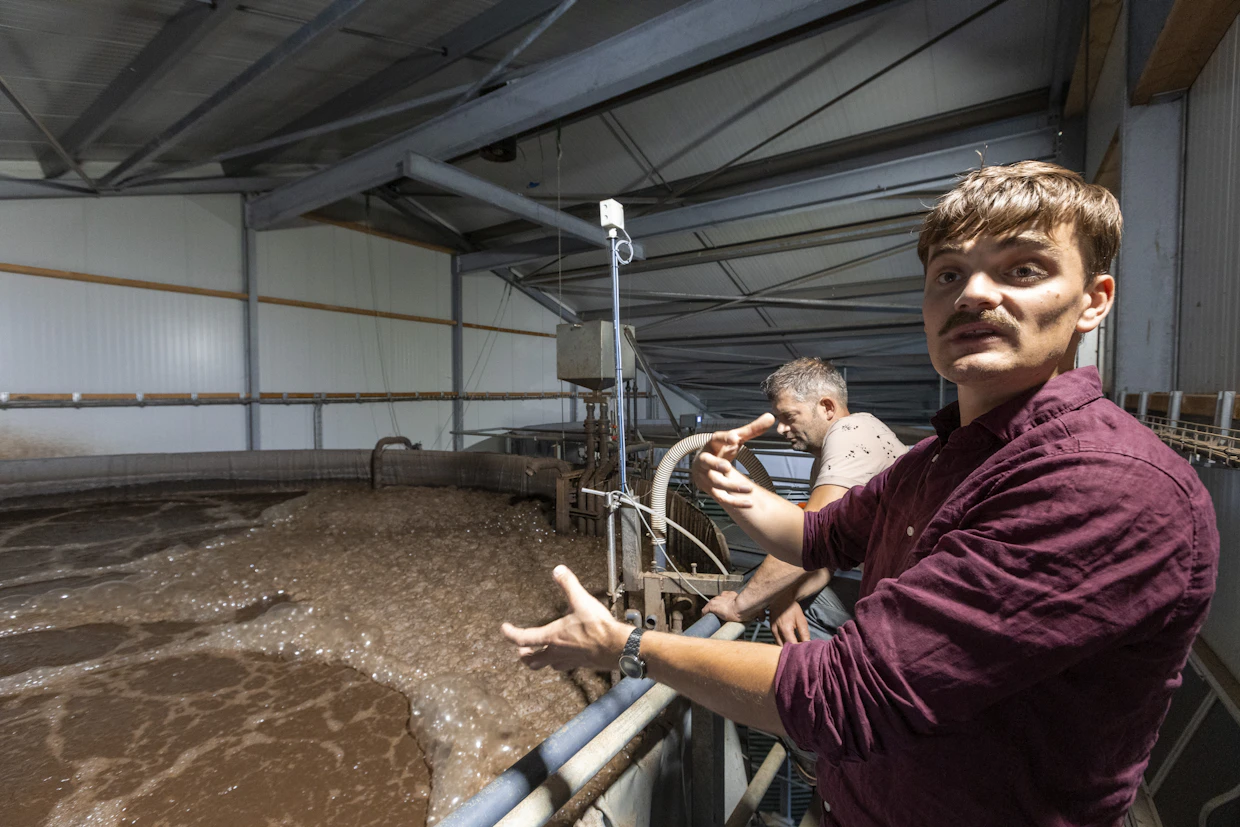 Karjatilan päästöjä leikkaavan järjestelmän toimittaneen Kamplanin insinööri Bas Scheepens (etualalla) korostaa, että William Meleundijksin (taustalla) sikatilalla on käytössä samanlainen veden puhdistusprosessi kuin jätevesiä puhdistavissa kunnallisissa vesilaitoksissa.