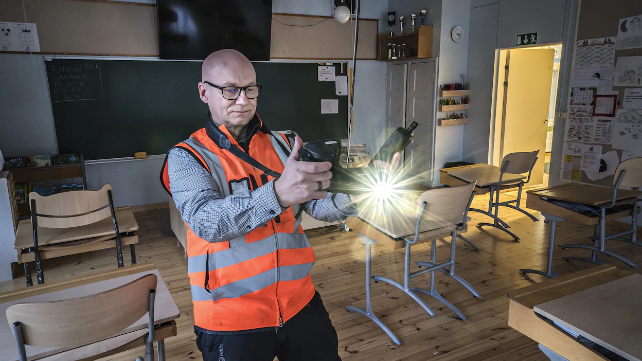 Rakennusterveysasiantuntija Esa Kemppainen lämpökuvaa kyläkoulun luokkatilaa Ilmajoen Munakassa. Lämpökameran lisäksi hän pitää vasemmassa kädessään ilmanpaine- ja lämpötilamittaria.