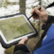 Metsäasiantuntija merkkaamassa metson soidinalueita maastotietokoneella tietokantaan.
