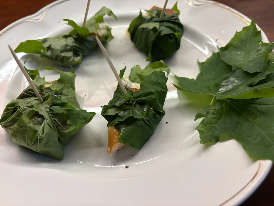 Vaahteranlehdet kätkevät sisäänsä puolikkaan, voidellun varhaisperunan ja lohta savustettuna tillillä, mustapippurilla ja suolalla.