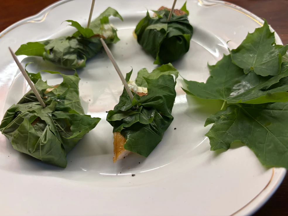 Vaahteranlehdet kätkevät sisäänsä puolikkaan, voidellun varhaisperunan ja lohta savustettuna tillillä, mustapippurilla ja suolalla.
