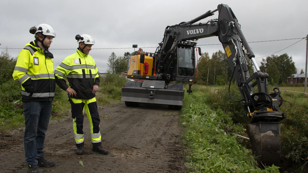 Toni Isokääntä ja Raimo Jussila seuraavat, kun kaapelia kaivetaan maahan Alavieskan Taluskylällä. Kaapeloitavalla alueella vanhat ilmajohdot puretaan maisemasta töiden valmistuttua.