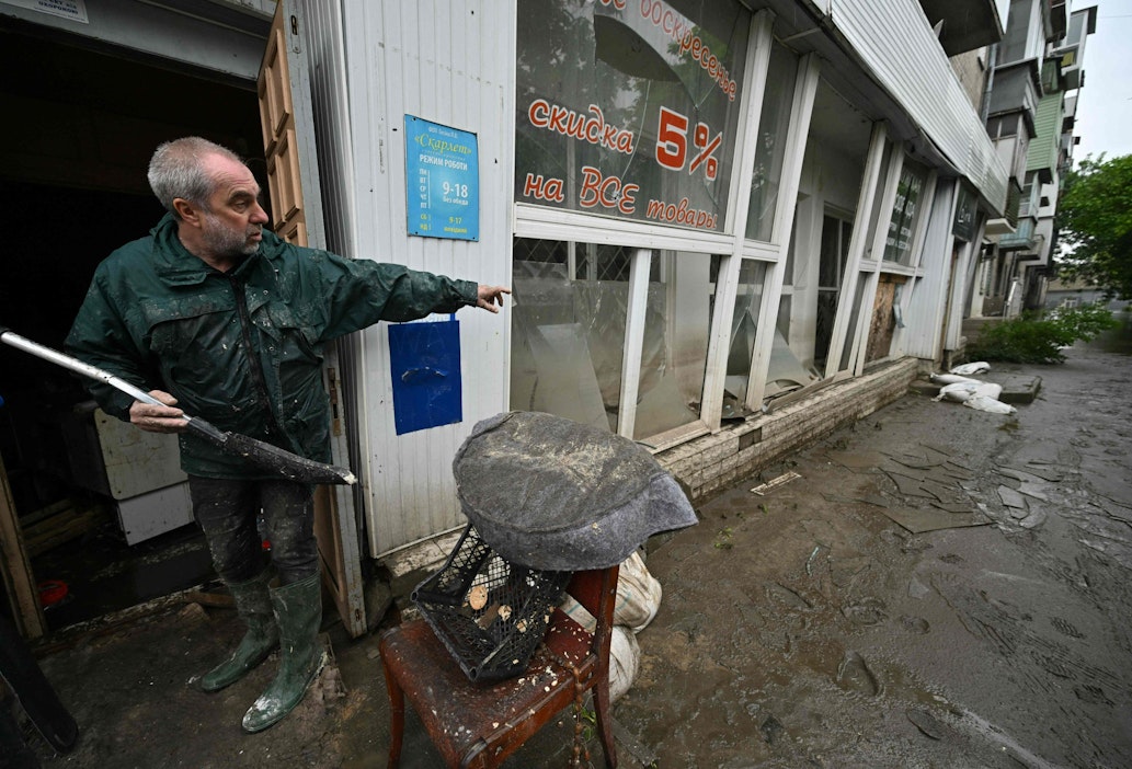 60-vuotias Hersonin asukas raivaa myymäläänsä tulvaveden laskiessa. LEHTIKUVA / AFP.