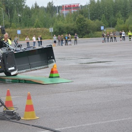 Ajotaitokilpailussa viistettiin kaltevalla alustalla kauhalla kerroksia. Oikealla juontaja Eemeli Linna. 