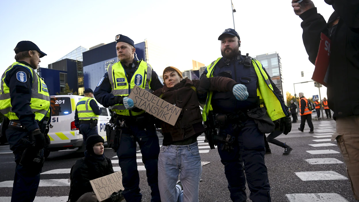 Liikenne jonoutui paikalla mielenosoituksen vuoksi ja poliisi kantoi muutamia mielenosoittajia ajoradalta poliisiautoon. Paikalla oli viisi poliisiyksikköä. LEHTIKUVA / Antti Aimo-Koivisto.