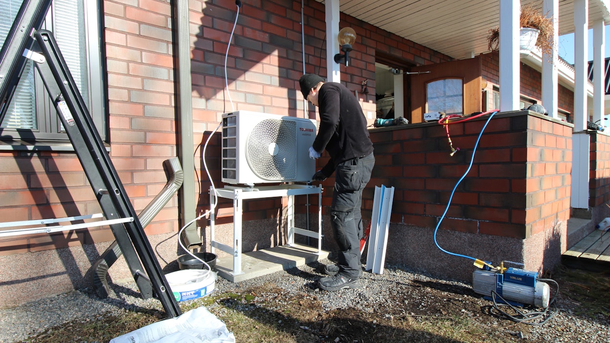 Asentaja Aleksi Nivara asentaa lämpöilmapumppua omakotitaloon.